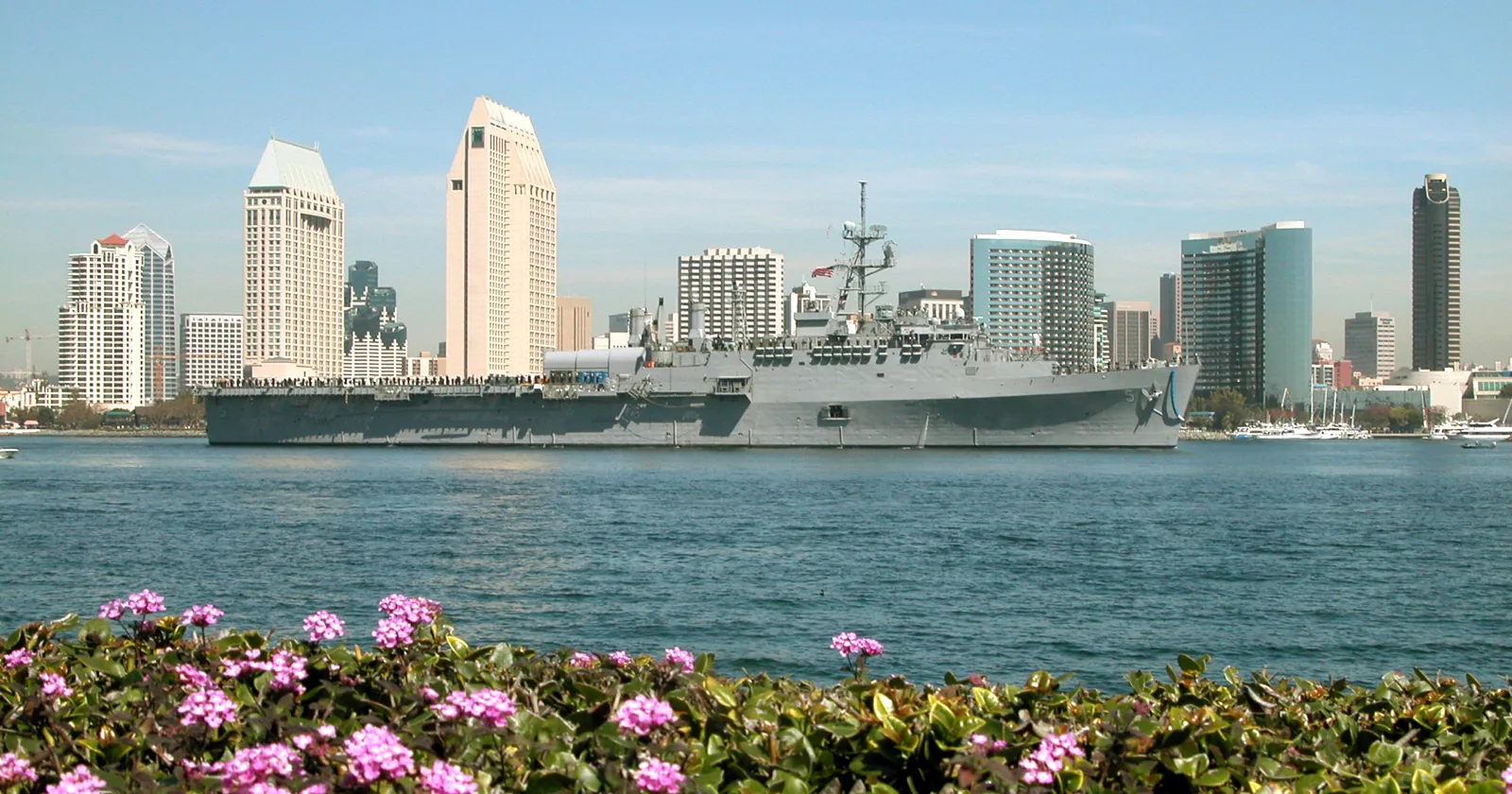 Navy ship transiting San Diego Bay past the downtown skyline, illustrating a military PCS home sale in San Diego