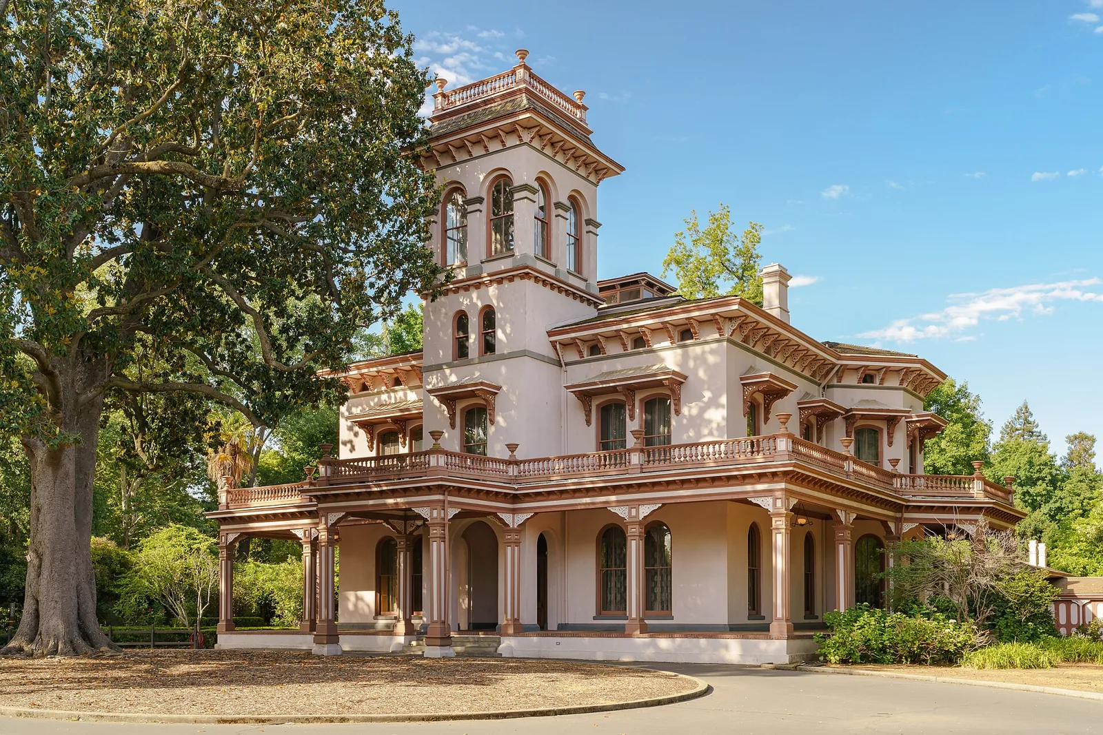 The pink Italianate Bidwell Mansion in Chico, with its three-story tower and arched veranda under a valley oak