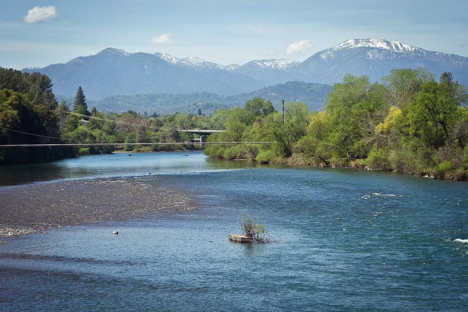 The Sacramento River flowing through Redding with the snow-capped Trinity Alps on the horizon