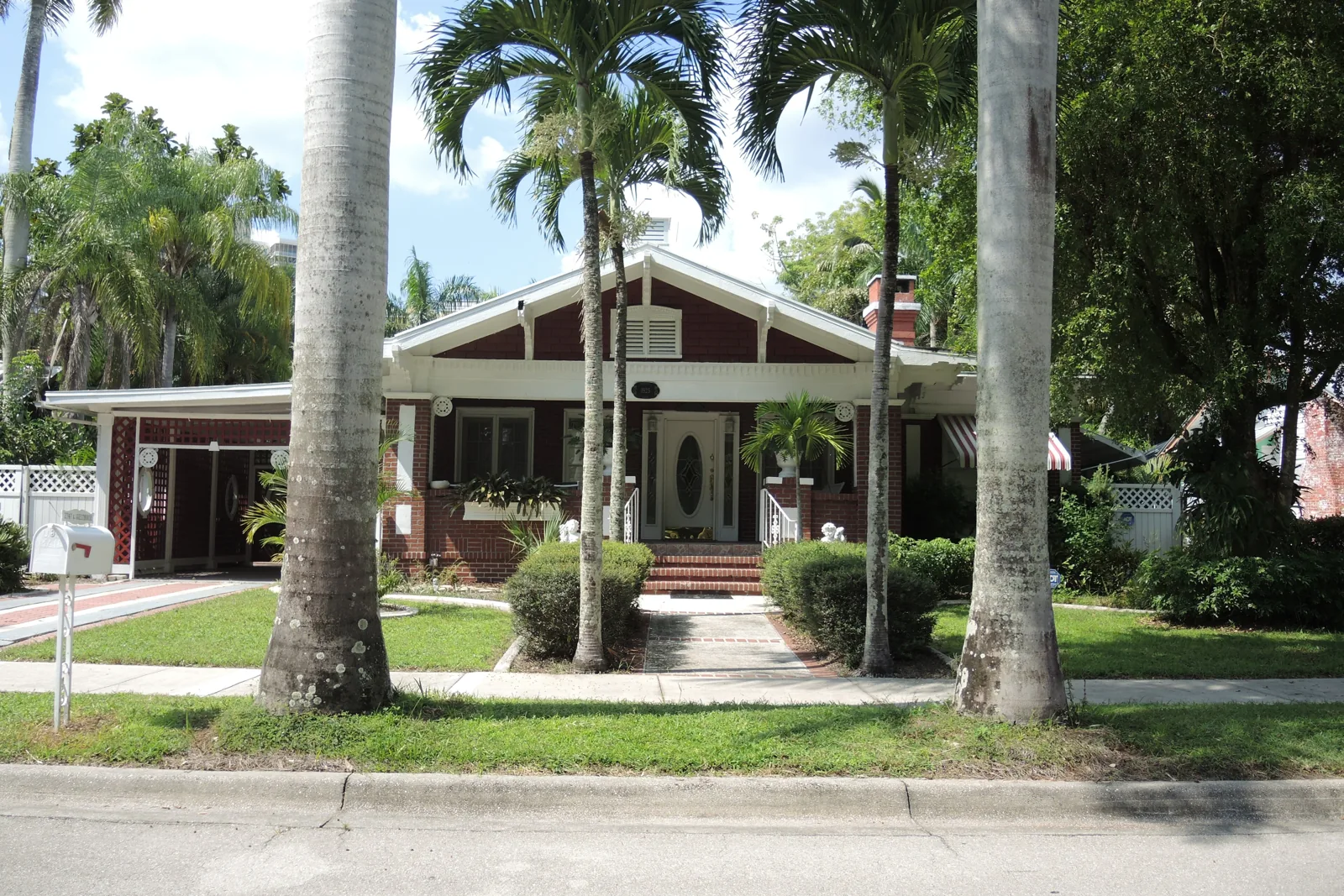 Red brick Craftsman bungalow behind royal palms in the Dean Park historic district of Fort Myers