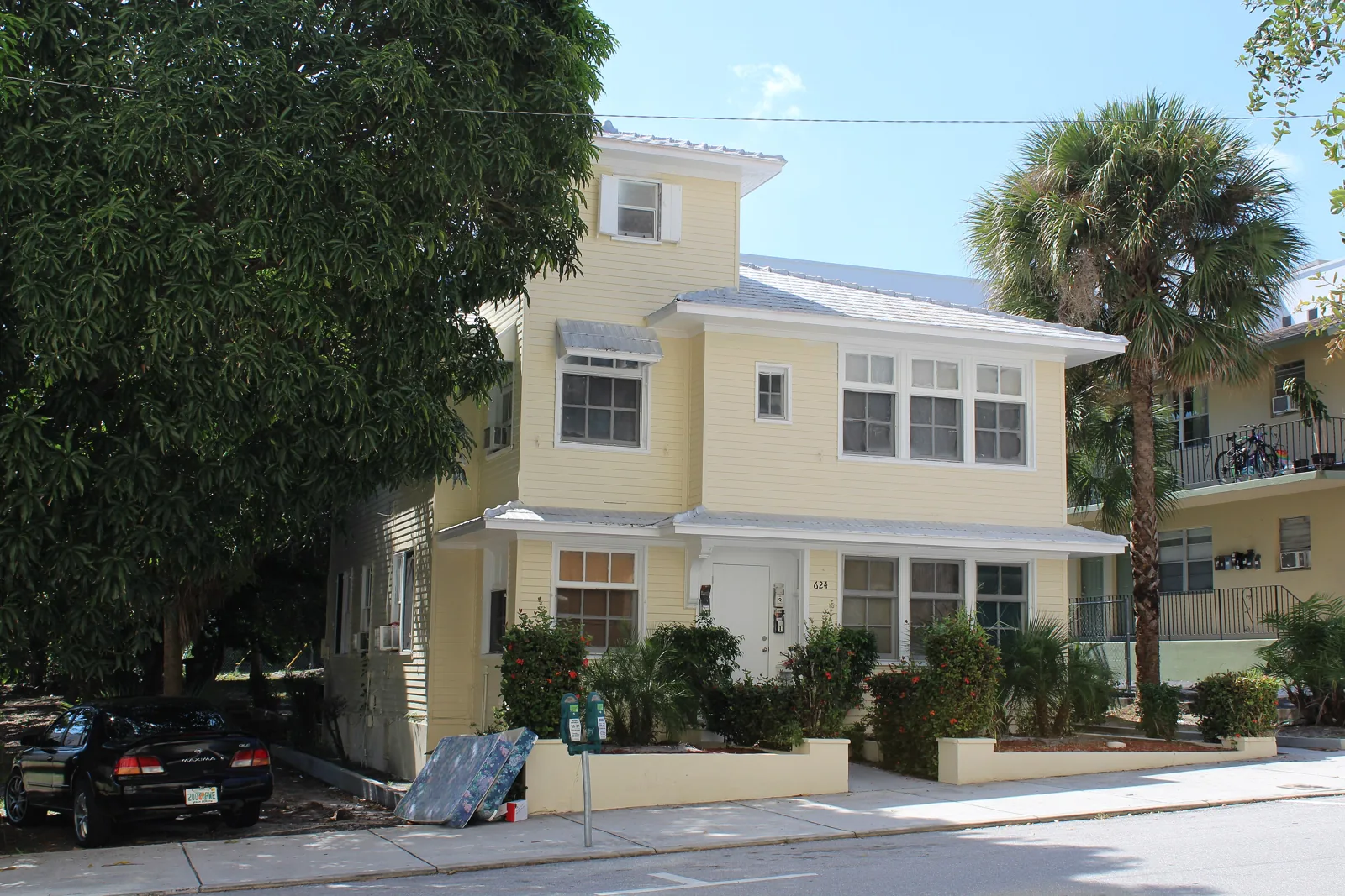 Yellow two-story wood-frame house built in 1921 with palms on Datura Street in West Palm Beach