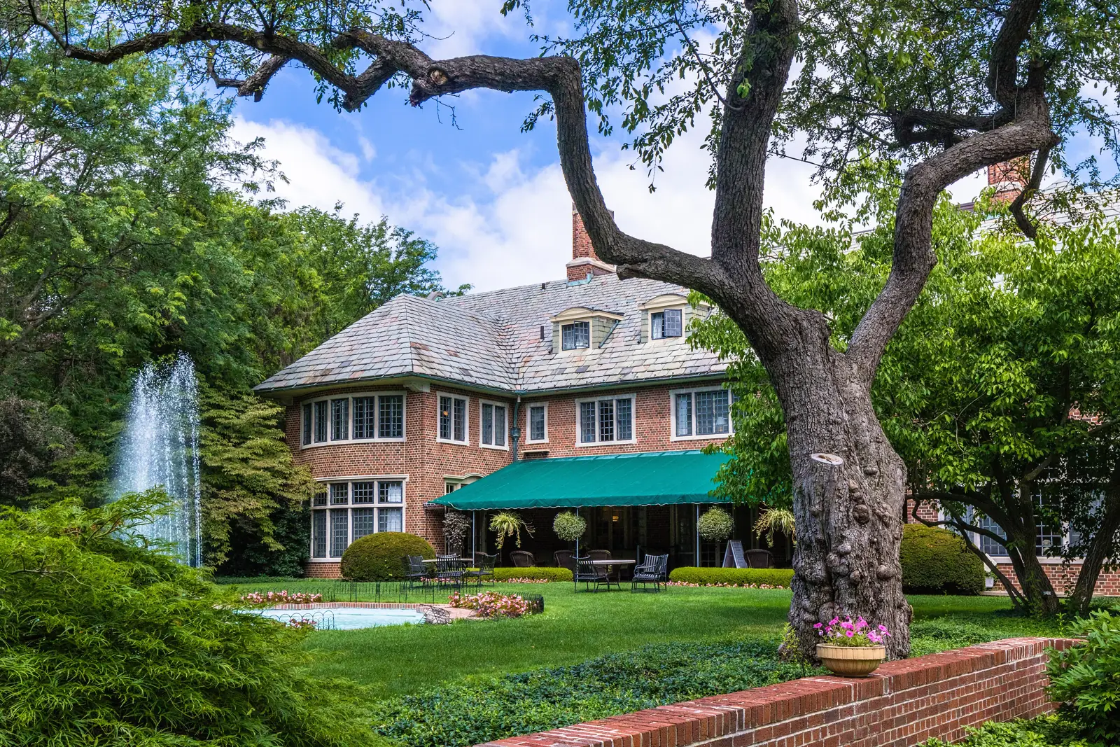 The brick Applewood Estate house, its lawn, and its fountain on the east side of Flint on a summer day