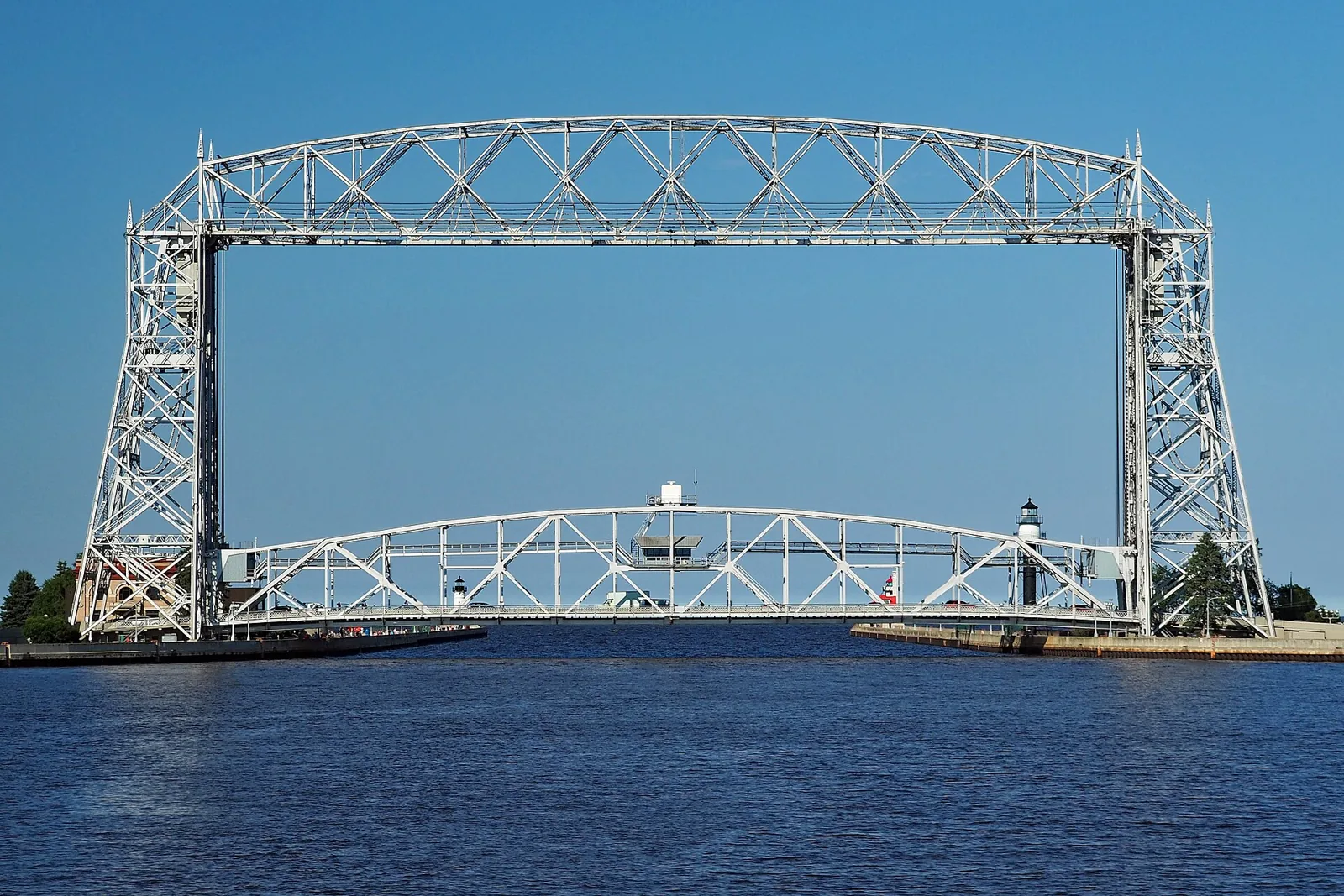 The Aerial Lift Bridge over the Duluth Ship Canal, its white steel span raised against a clear blue sky above Lake Superior