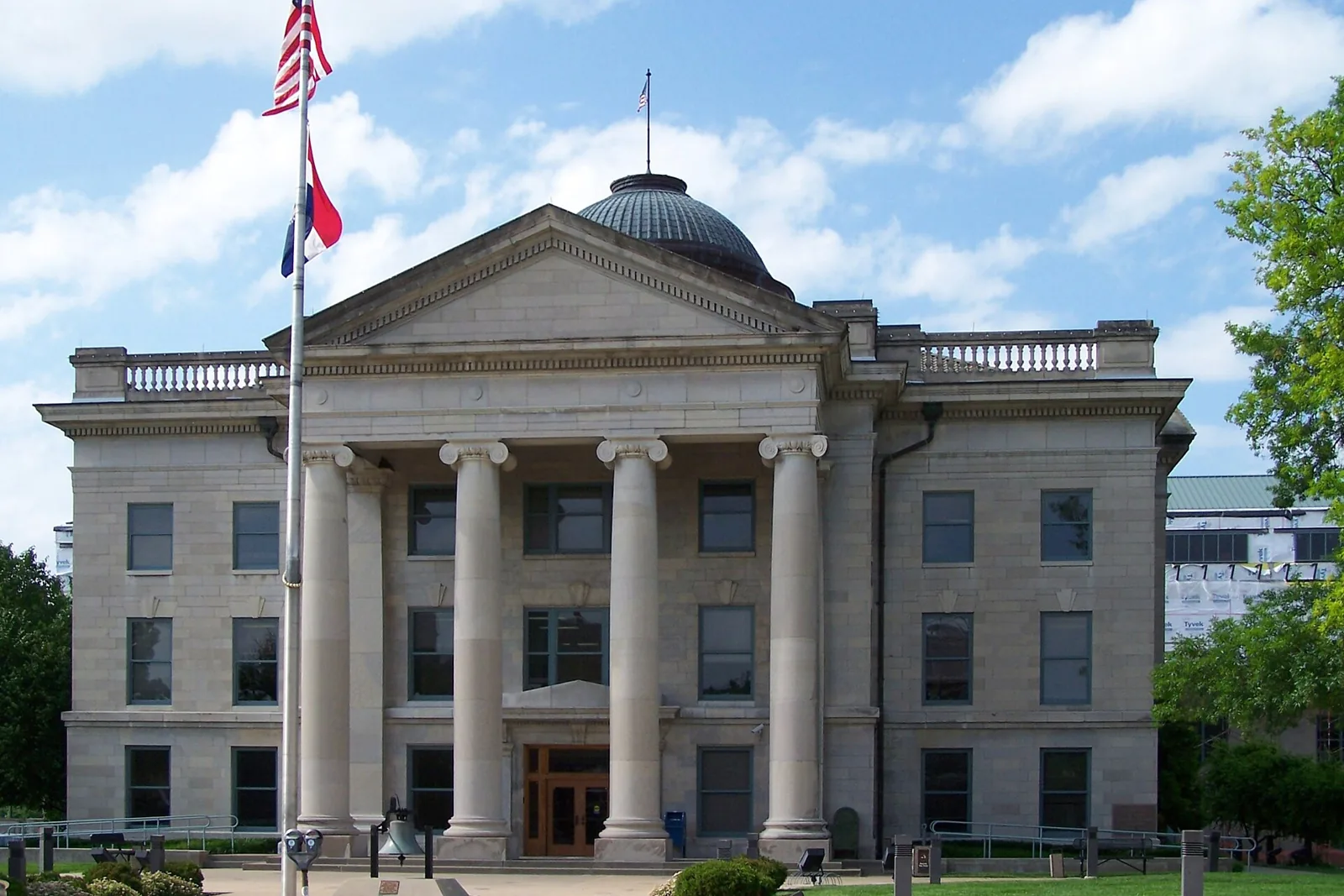 The limestone Boone County Courthouse in downtown Columbia, Missouri, with its columned portico, green dome, and flags out front