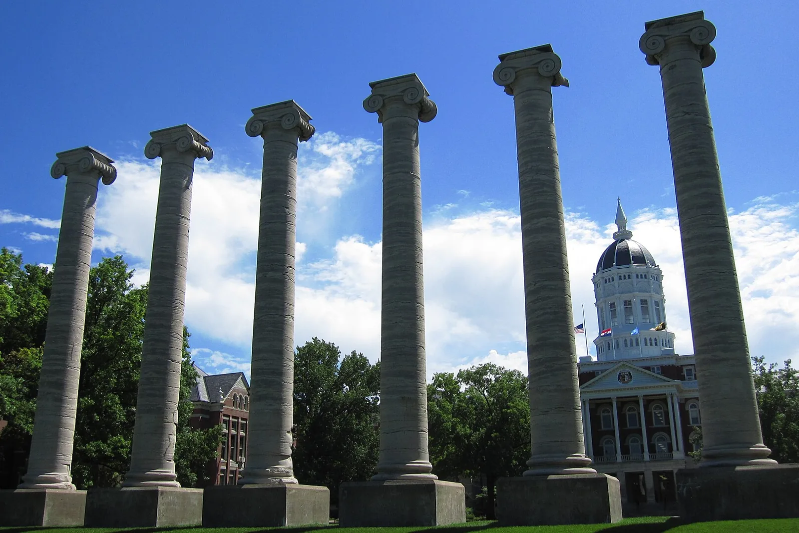 The six Ionic columns on the Francis Quadrangle with the white dome of Jesse Hall behind them at the University of Missouri in Columbia, under a blue sky