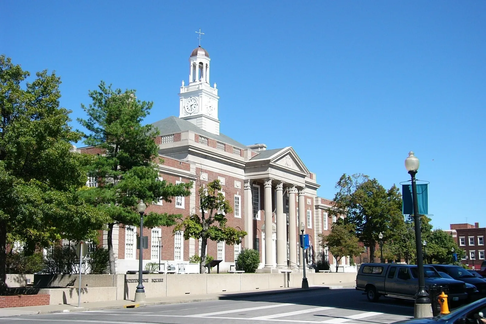 Brick Jackson County courthouse with a white clock tower and columned entrance on Independence Square in Independence, Missouri, under a clear blue sky.