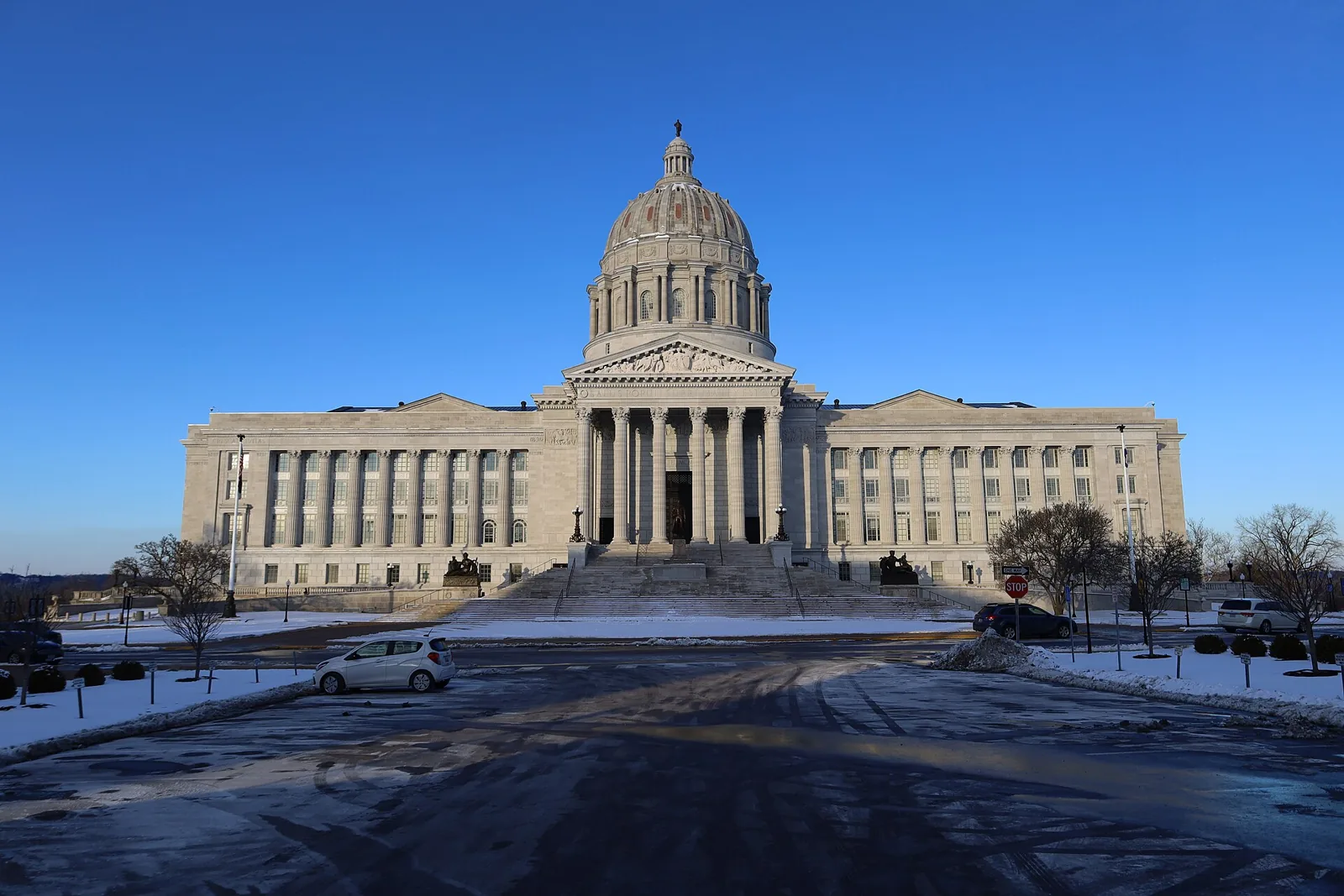 Domed Missouri State Capitol in Jefferson City rising above its columned facade and steps against a deep blue sky.
