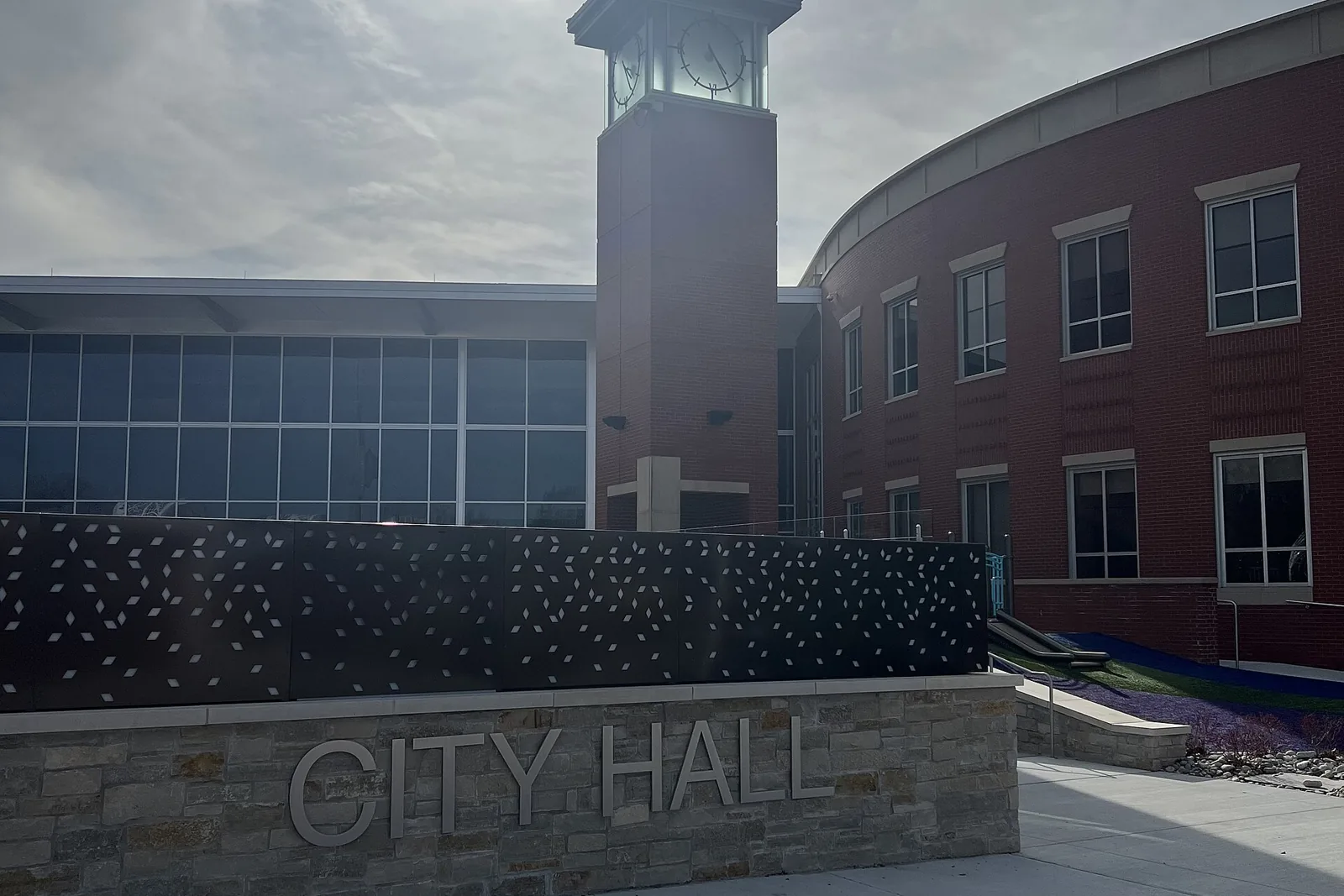 The brick clock tower and curved entrance of Lee's Summit City Hall in Lee's Summit, Missouri, under a hazy sky