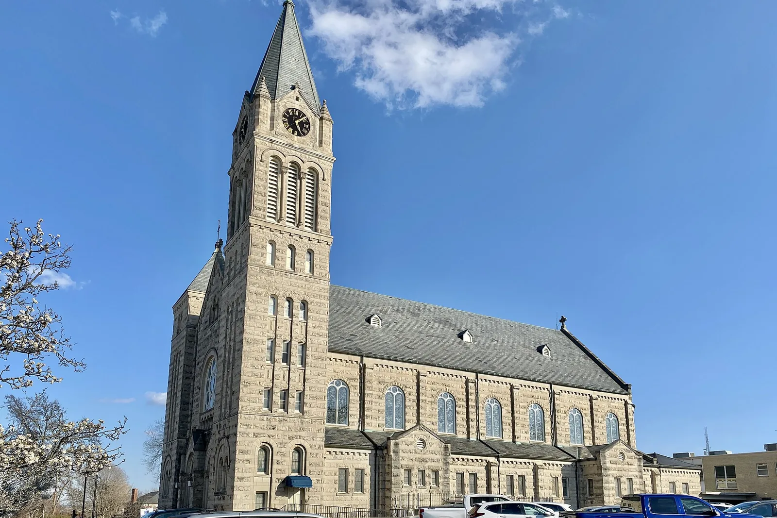 The limestone tower and slate roof of St. Charles Borromeo Catholic Parish Church in St. Charles, Missouri, against a clear blue sky in early spring