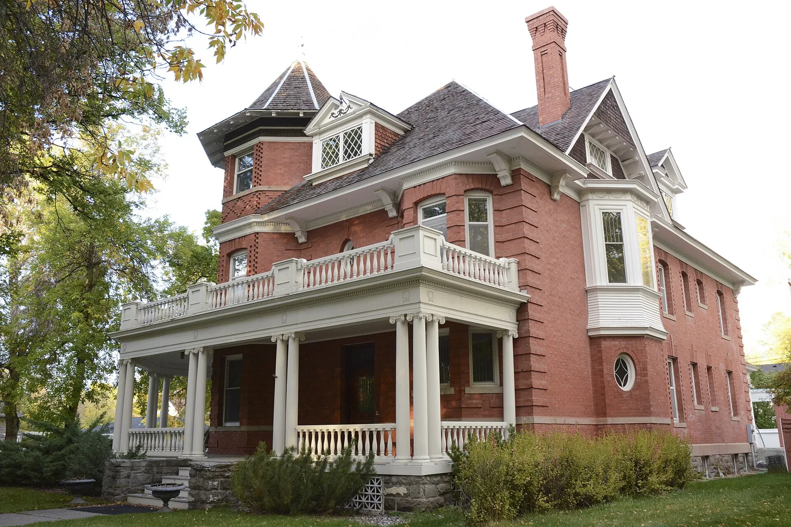 A brick Queen Anne house with a corner turret and a columned wraparound porch in the Bon Ton Historic District of Bozeman