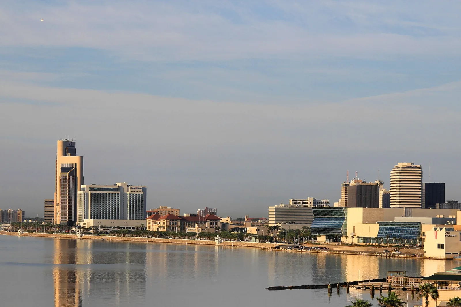 Downtown Corpus Christi skyline across Corpus Christi Bay in early morning light, with the bayfront and marina in the foreground