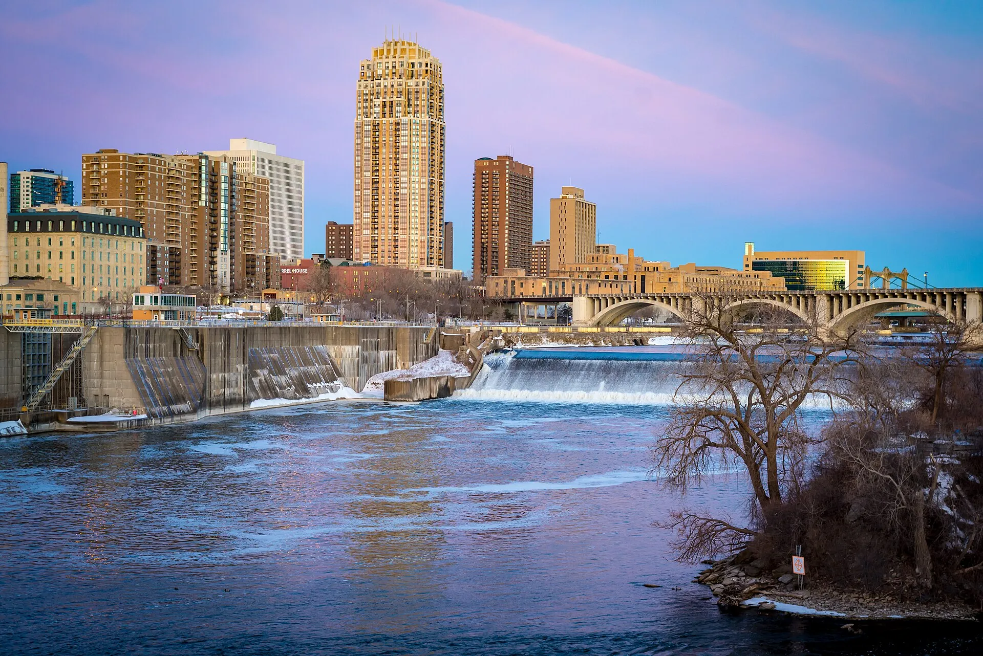 The downtown Minneapolis skyline above St. Anthony Falls and the Third Avenue Bridge at dusk