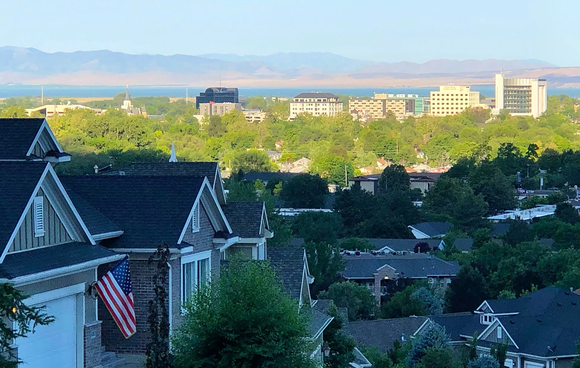 Rooftops of houses on the bench above downtown Provo, Utah, with the office towers of the city center, Utah Lake, and the Lake Mountains beyond