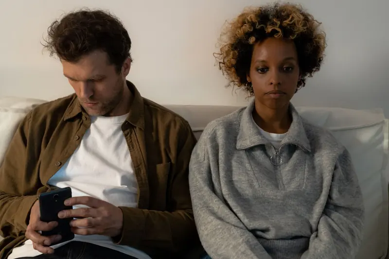 A couple sitting apart on a sofa, each lost in thought
