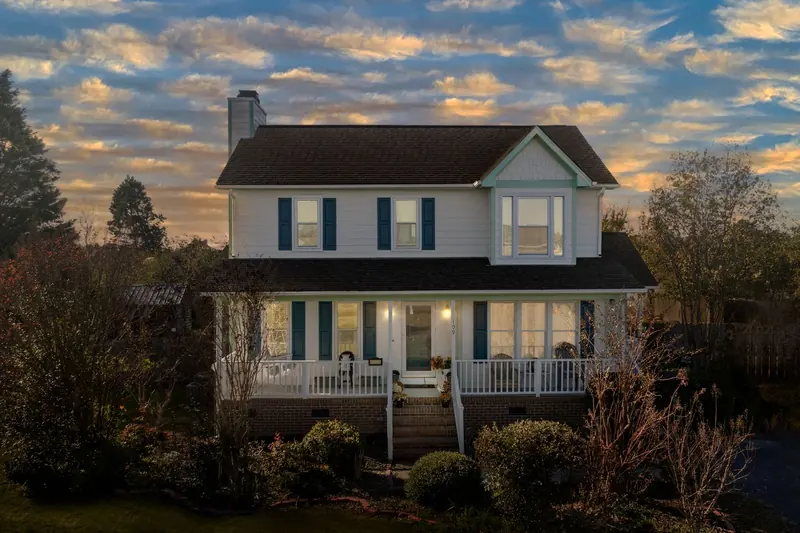 A two-story house with its lights on at dusk